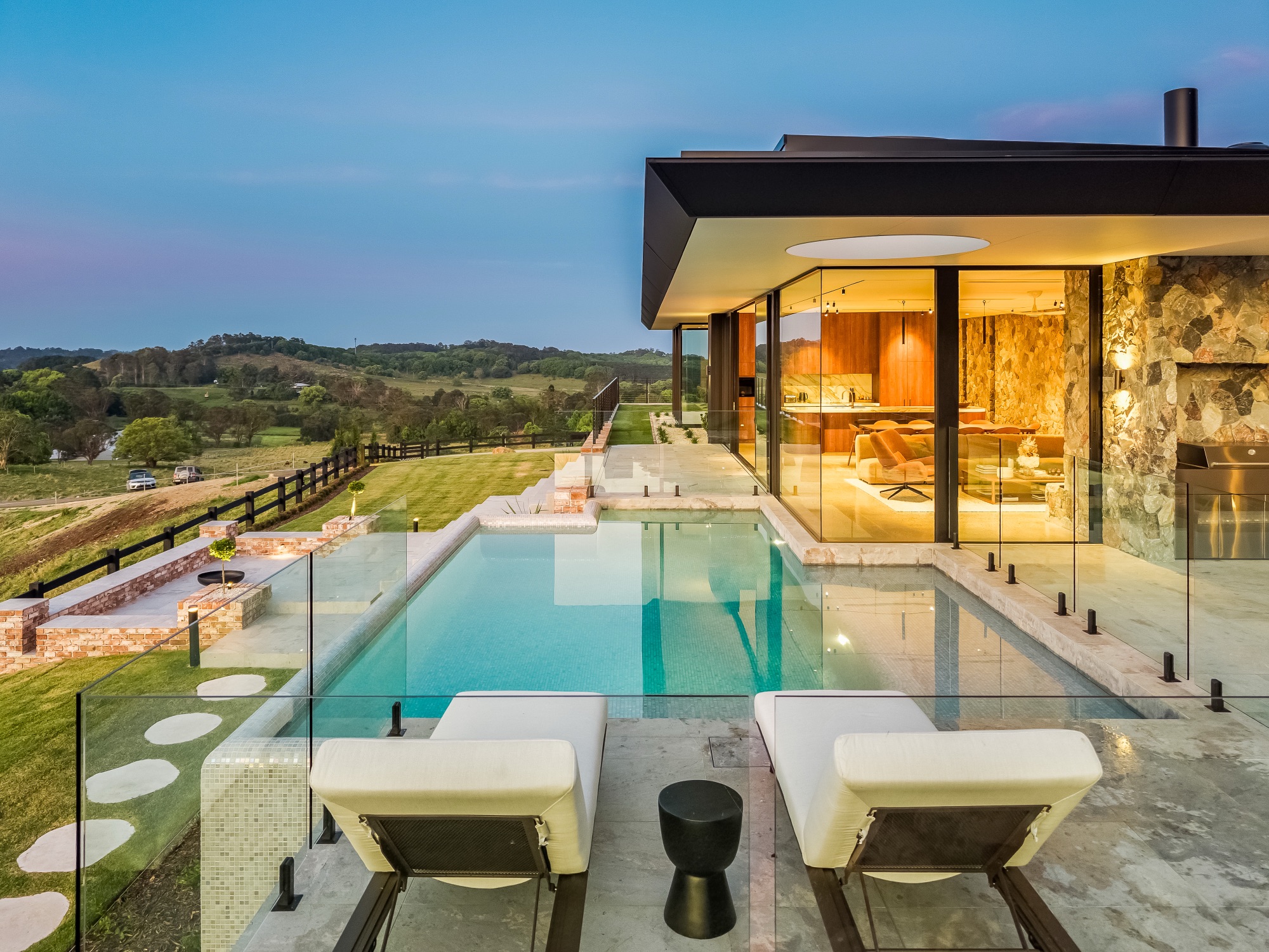 Pool terrace at twilight with interior warmth and dusk sky