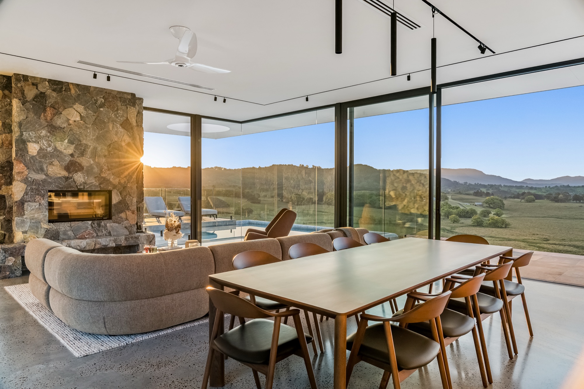 Open plan dining and living at sunset with pool and mountain backdrop