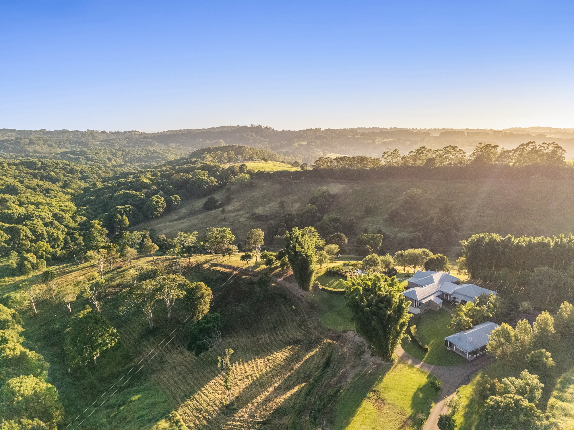 Wide aerial at sunrise showing homestead compound and 58 acres with Nightcap Ranges