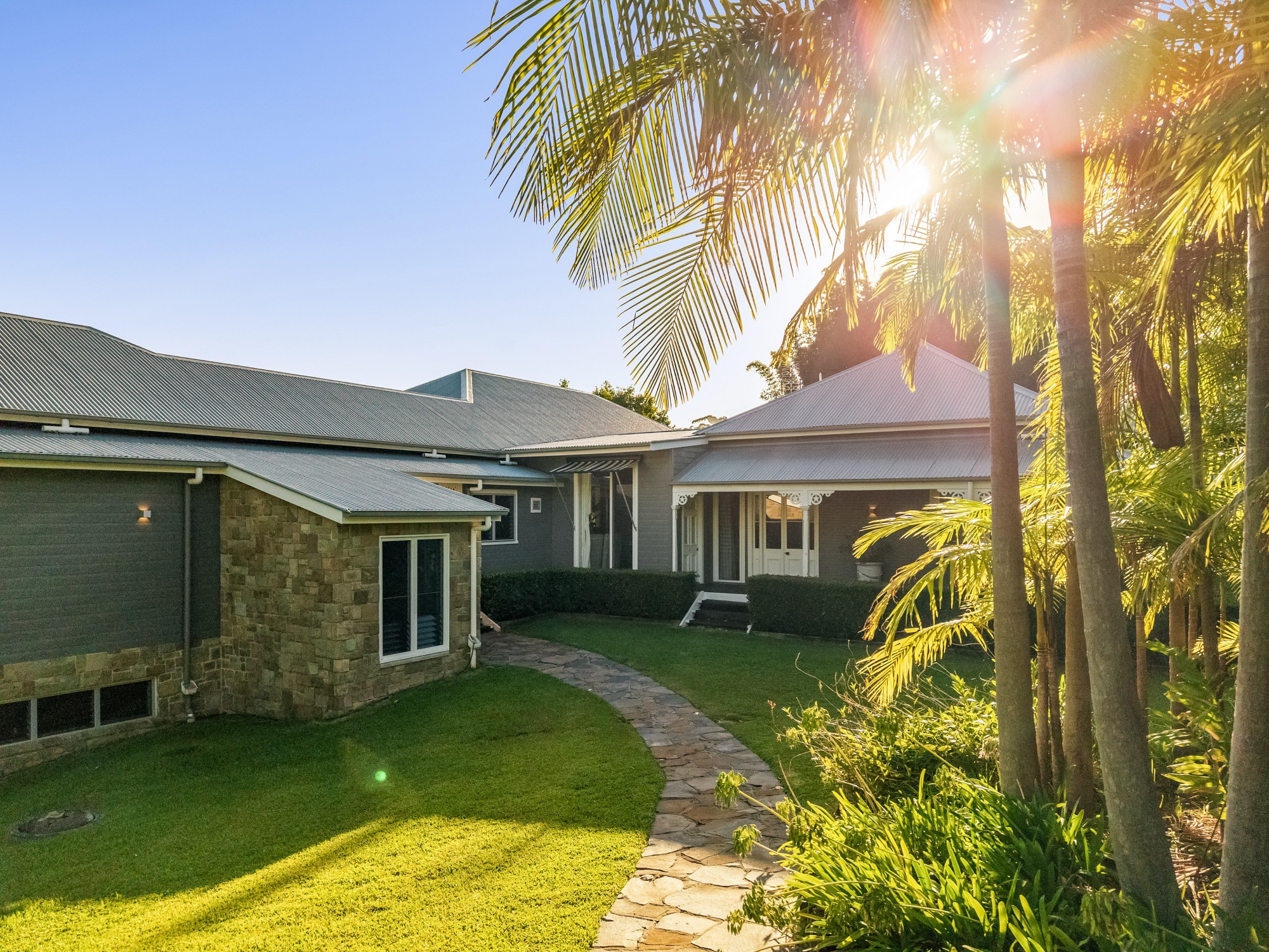 Rear facade at golden hour with stone pathway and tropical landscaping