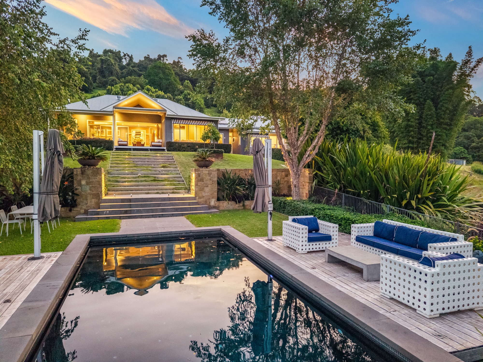 Twilight view from pool showing homestead, stone steps and garden lighting