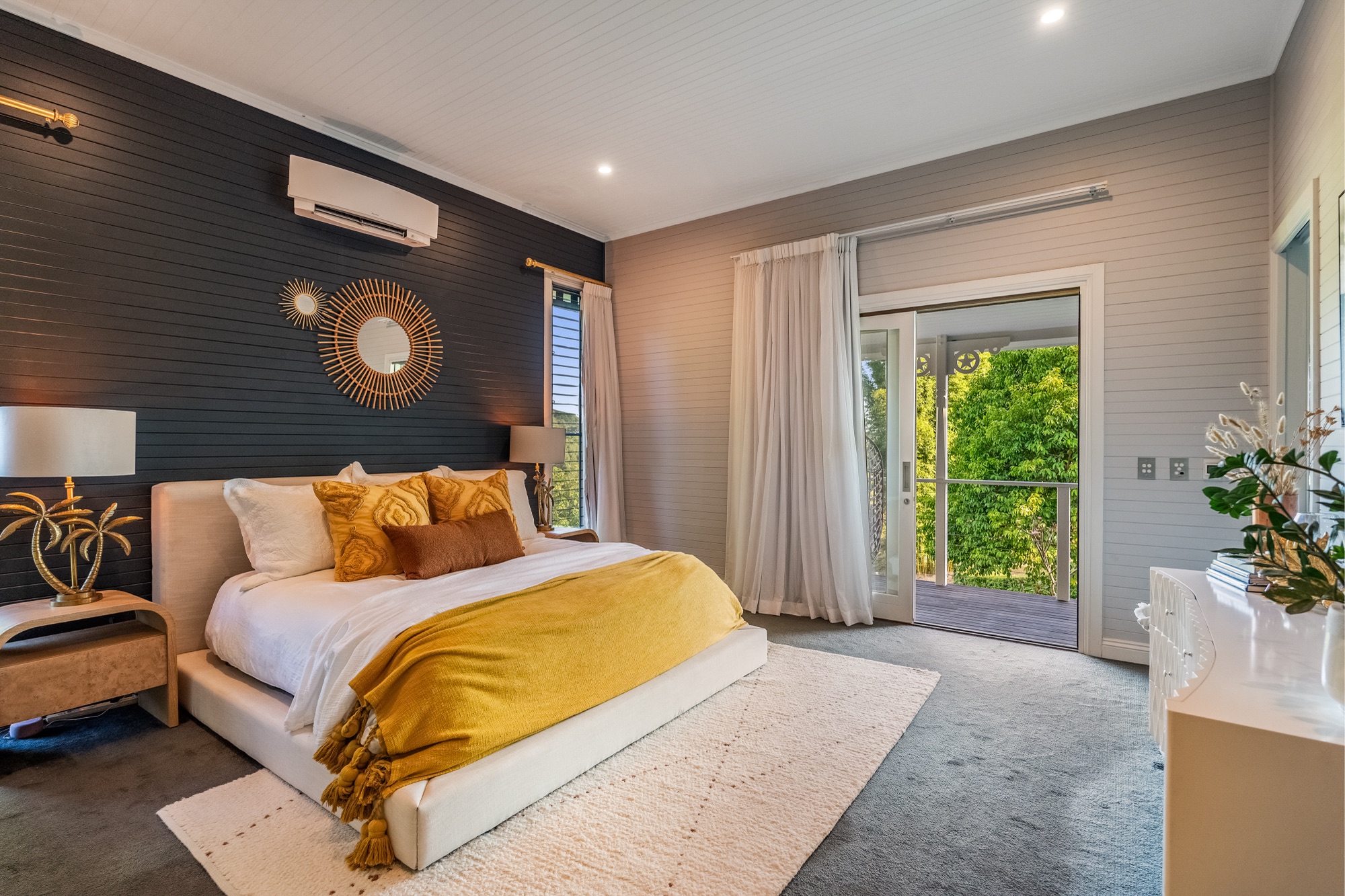 Master bedroom with dark feature wall, gold styling and garden access
